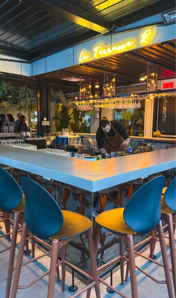 Bar de la terrasse R avec logo en néon et serveur