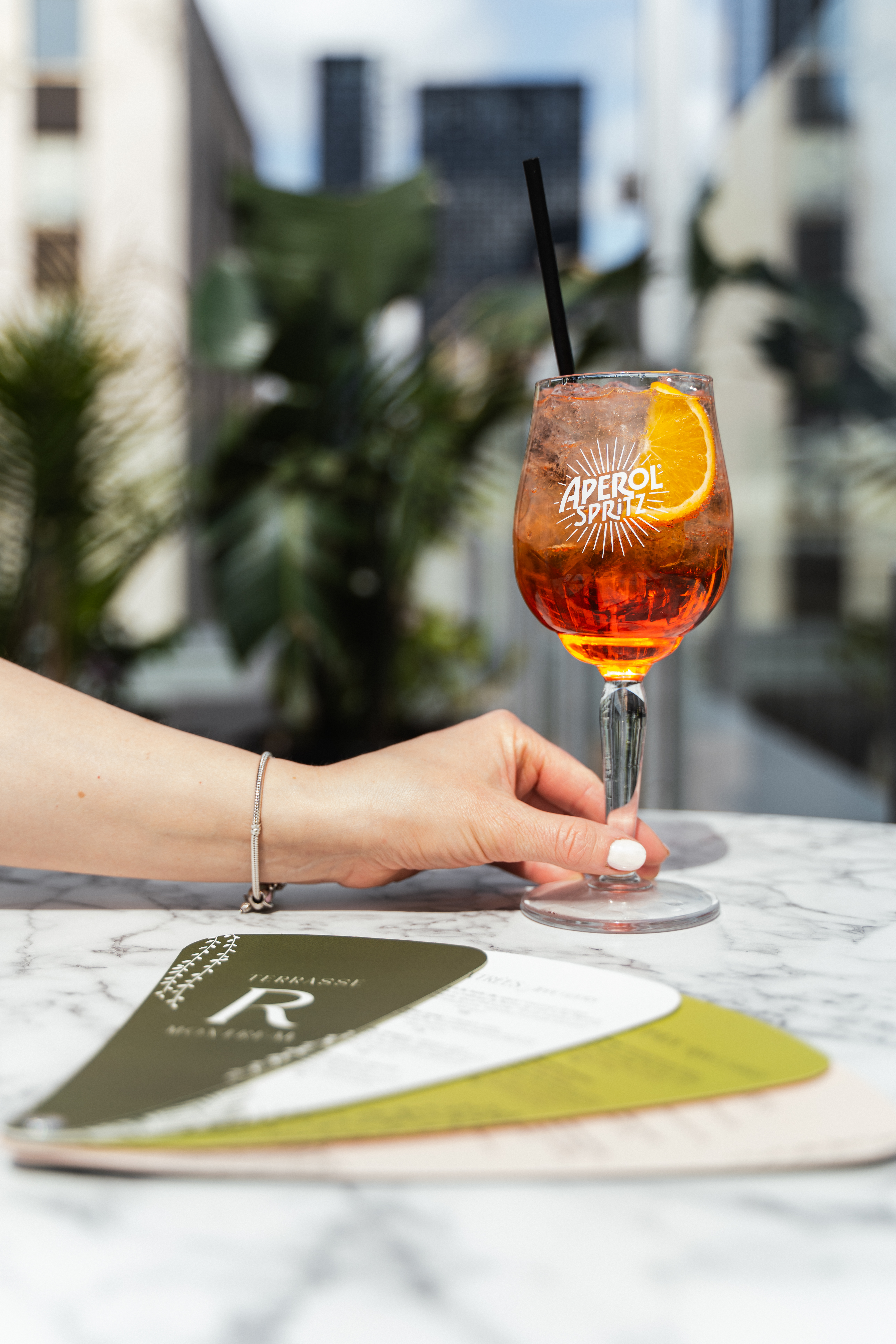 Une main tient un Aperol Spritz